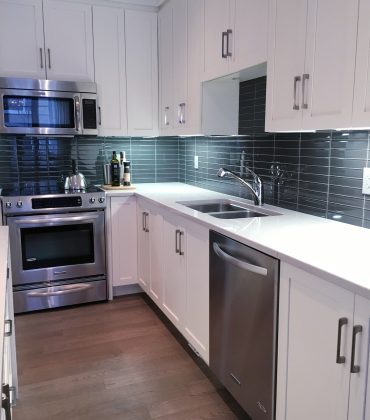 Modern kitchen with white furniture and glass tiles for backsplash